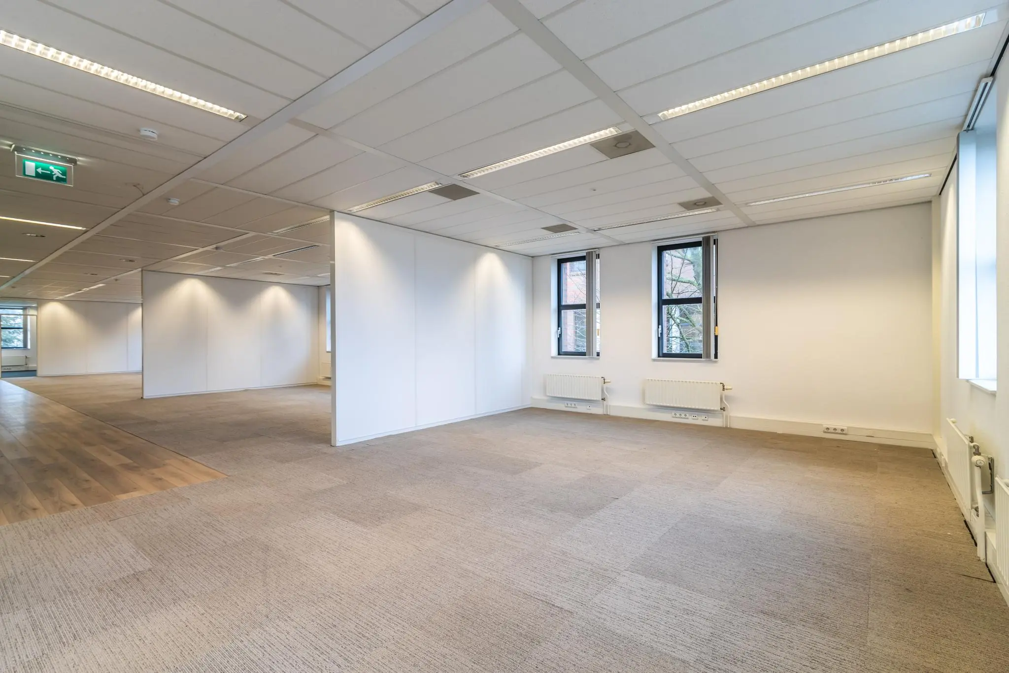 Leeg kantoorpand aan de Lange Dreef met systeemplafond, tapijtvloer en grote ramen.